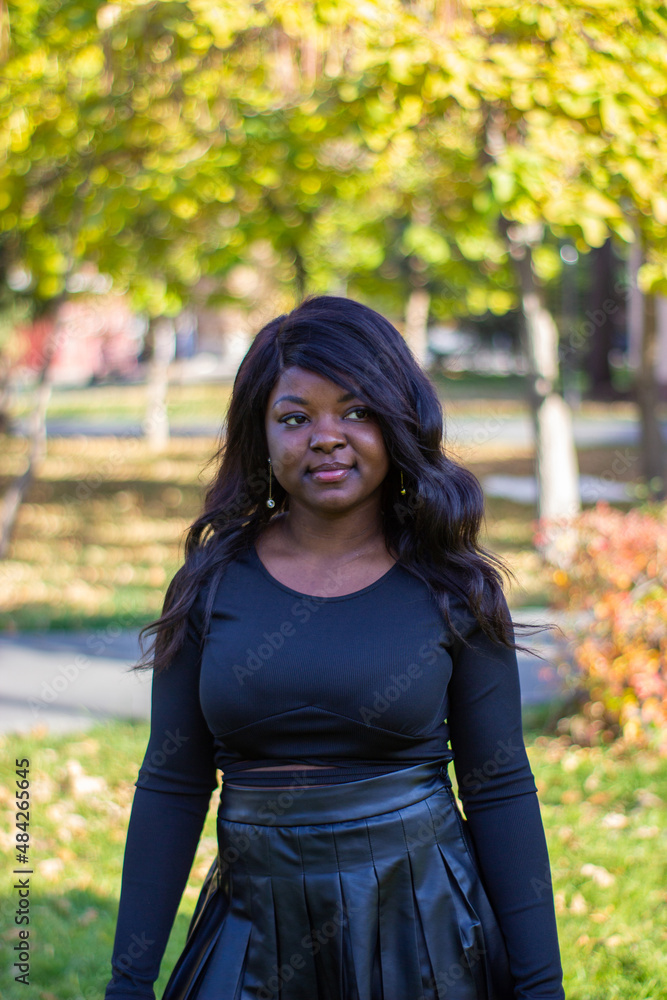 A beautiful African lady wearing a black dress in a park. A beautiful African lady wearing a black dress in a park.