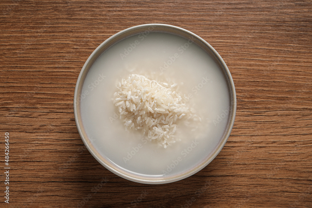 Rice soaked in water on wooden table, top view Rice soaked in water on wooden table, top view
