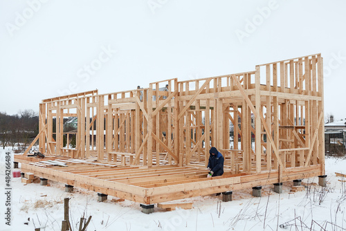 Wood frame house erection, bare frame with pile foundation, winter season, carpenter photo