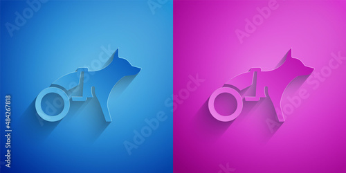 Paper cut Paralyzed dog in wheelchair icon isolated on blue and purple background. Paper art style. Vector