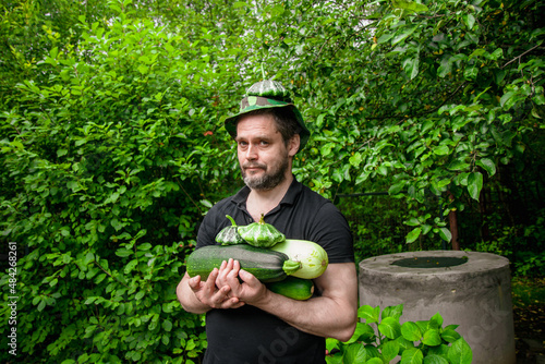 Portrait of a man harvesting organic vegetables.The gardener holds ripe, juicy zucchini in his hands	
