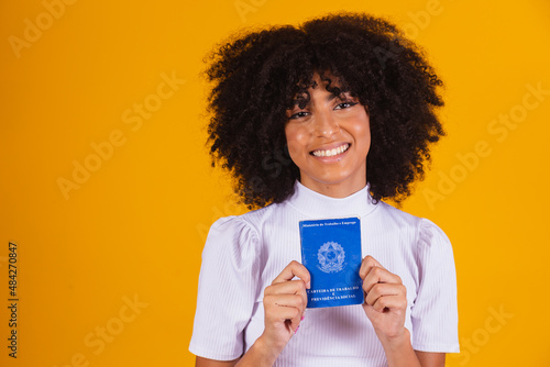 Young afro woman holding a Brazilian work card. Labor reform, fgts, salary and formal worker concept photo