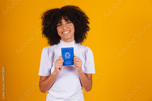 Young afro woman holding a Brazilian work card. Labor reform, fgts, salary and formal worker concept photo
