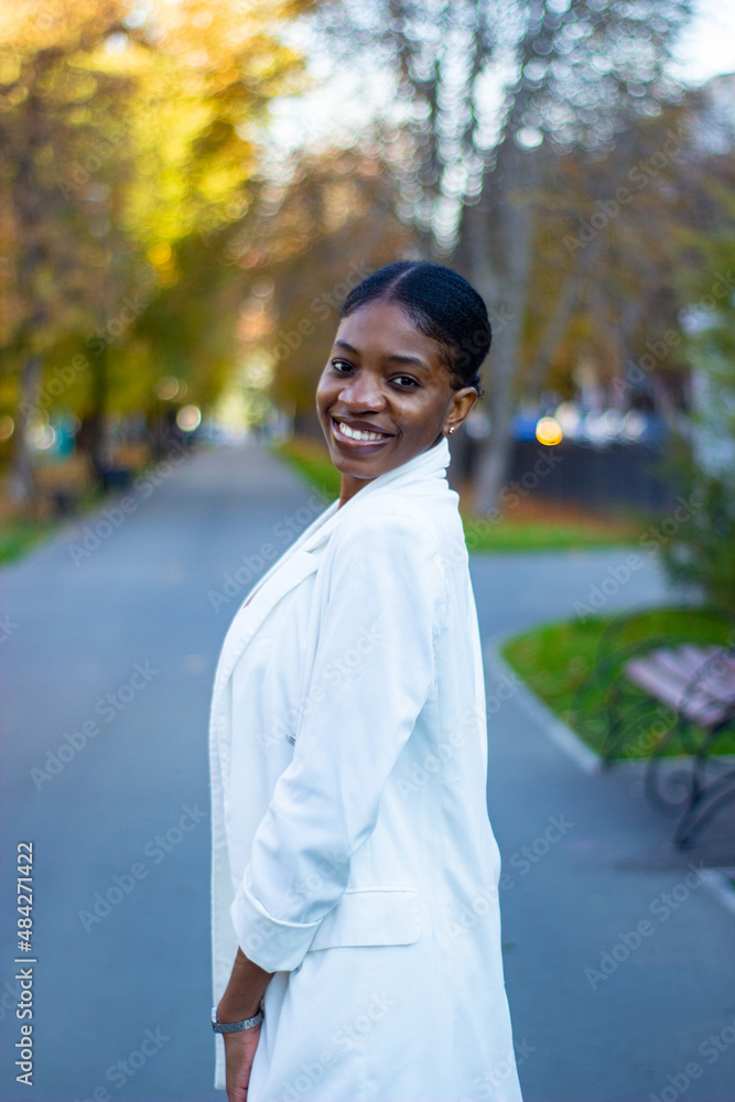 Side view of a beautiful African lady wearing a white outfit in a park. Side view of a beautiful African lady wearing a white outfit in a park.