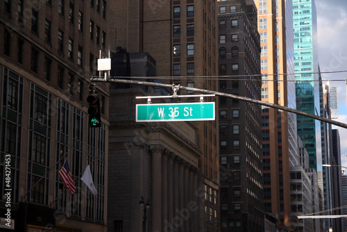 Green big West 35th Street sign hanging on a arch pole in the streets of midtown Manhattan