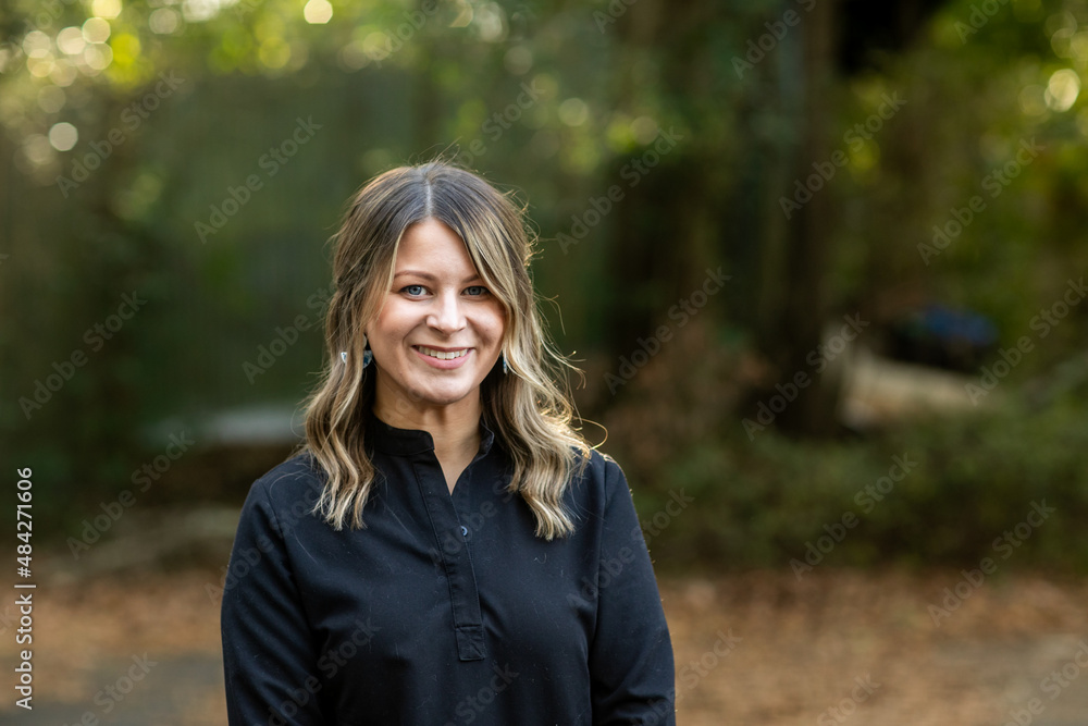 A young cosmetologist standing outside among green trees for a headshot with copy space A young cosmetologist standing outside among green trees for a headshot with copy space