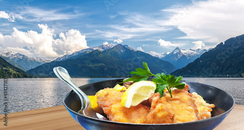 Photography Traditional austrian food (Wiener schnitzel) against Zell am see village with la