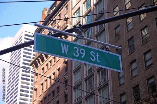 Green big West 39th Street sign hanging on a arch pole in the streets of midtown Manhattan