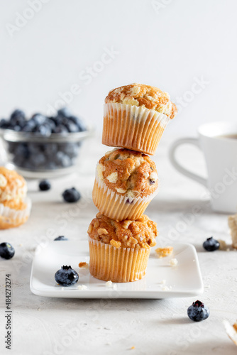 Homemade stack of blueberry muffins on white plate with coffee cup and berries