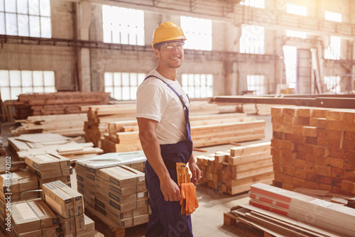Cheerful male worker standing by construction materials