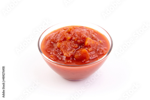 Chopped tomatoes in tomato juice in glass bowl isolated on white