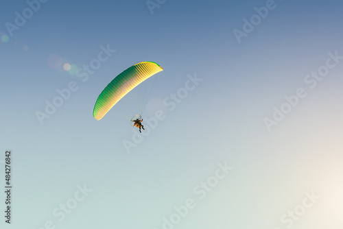 Motorized paraglider flies in the blue sky, extreme sports