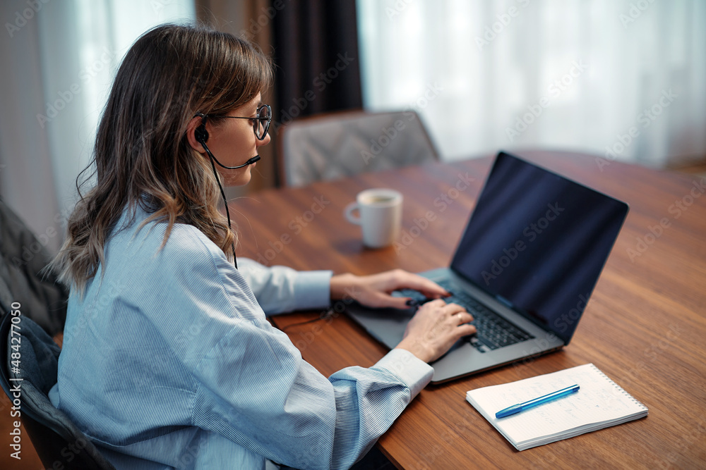 Female call center agent operator in headset ready to accept video call looking at laptop, sit at desk. Customer service Female call center agent operator in headset ready to accept video call looking at laptop, sit at desk. Customer service