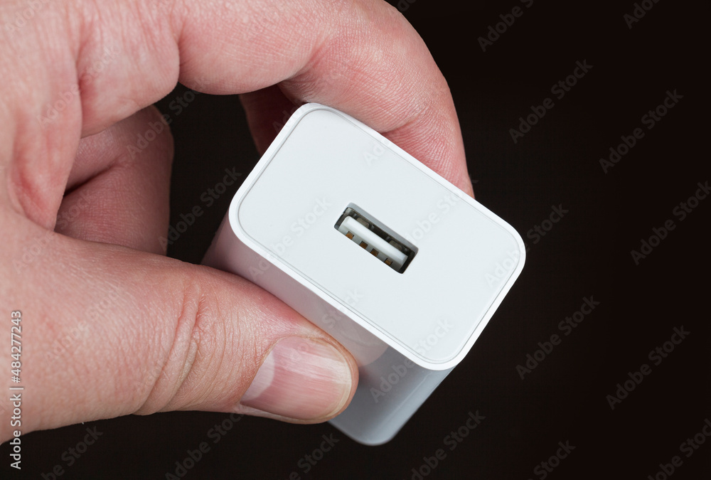 Hand holding USB electronic device charger on black background Hand holding USB electronic device charger on black background