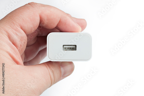 Hand holding USB electronic device charger on white background