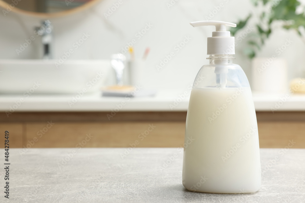 Dispenser of liquid soap on light grey table in bathroom, space for text Dispenser of liquid soap on light grey table in bathroom, space for text