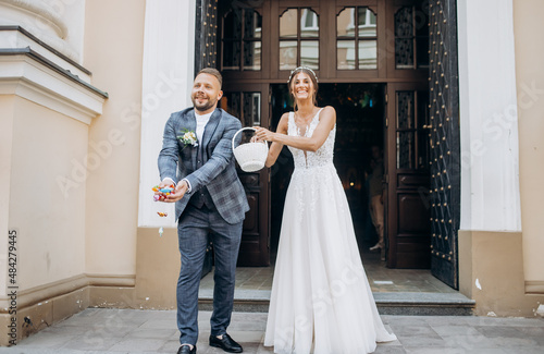Happy newlyweds throw candy out of the basket before leaving the church.