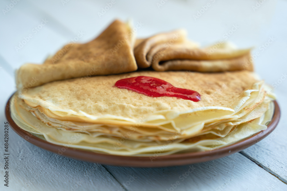 Crepes, thin pancakes on a plate on a white wooden table Crepes, thin pancakes on a plate on a white wooden table