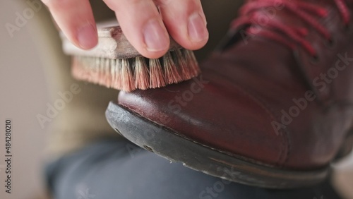 Caucasian Male Polishing Brown Leather Boots Shoes with Soft Brush After Waxing Waterproffing and Impregnating with Shoe Shine Wax