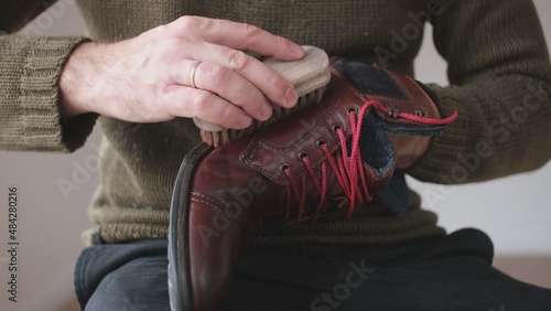 Caucasian Male Polishing Brown Leather Boots Shoes with Soft Brush After Waxing Waterproffing and Impregnating with Shoe Shine Wax