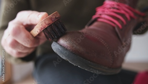 Caucasian Male Polishing Brown Leather Boots Shoes with Soft Brush After Waxing Waterproffing and Impregnating with Shoe Shine Wax photo