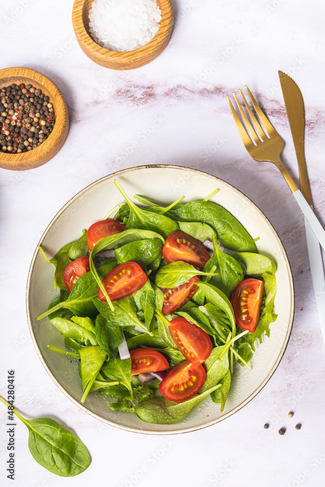Summer green salad in white bowl plate on grey table Summer green salad in white bowl plate on grey table
