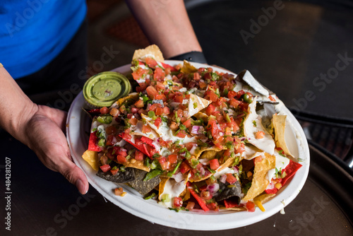 Waitress holding a platter of nachos and guacamole photo