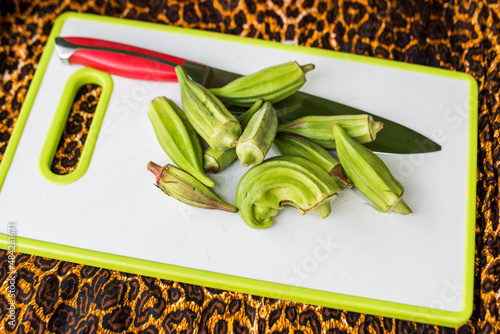 Freshly harvested okra on cutting board with knife photo