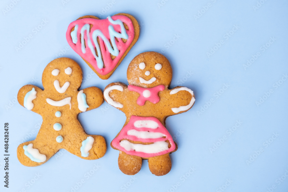 Boy and girl gingerbread couple and heart on the blue background with copy space for St Valentines Day. Boy and girl gingerbread couple and heart on the blue background with copy space for St Valentines Day.