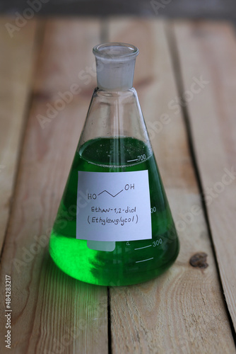 Conical flask with green aqueous solution of ethylene glycol, and its chemical structural formula.
