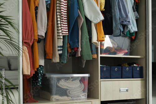 Wardrobe closet with different stylish clothes and home stuff in room. Fast fashion