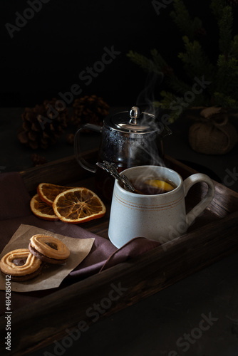 Hot tea cup with tea pot and cookies on wooden tray. 
