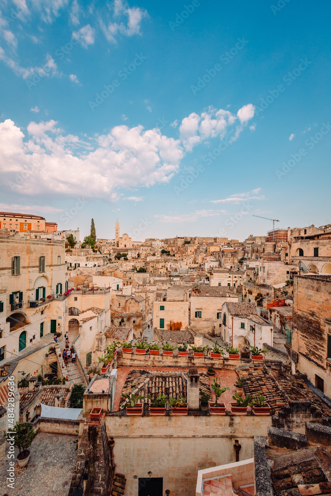 Wide view of the Sassi of Matera from the Luigi Guerricchio Belvedere, blue sky with clouds, vertical