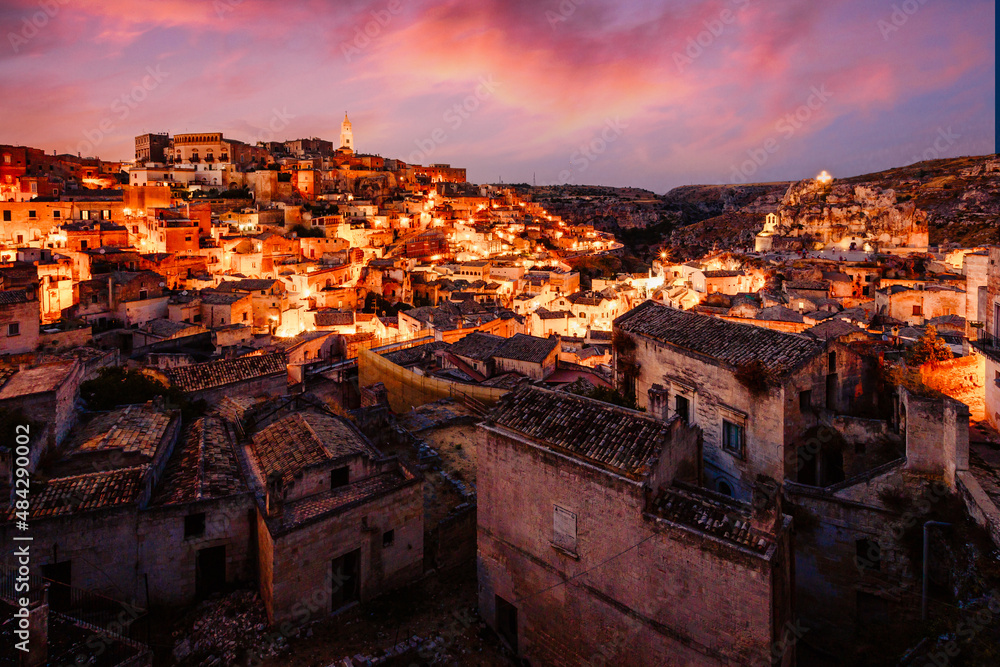 Wide view of Piazzetta Pascoli, Belvedere of Matera on the Sasso Caveoso, at sunset with illuminated houses and a spectacular sky