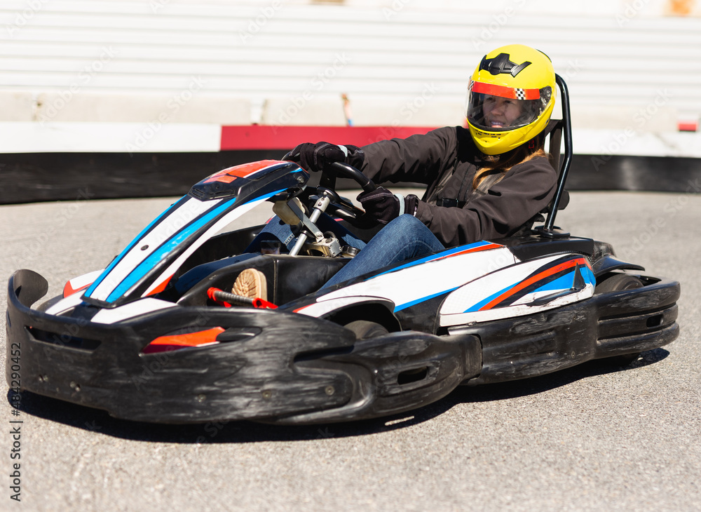 Young female in helmet driving go-kart car in sport club outdoor