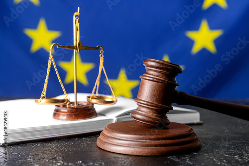 Gavel of judge with scales of justice and book against European Union flag photo