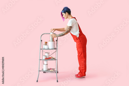 Female painter with ladder and cans on pink background © Pixel-Shot