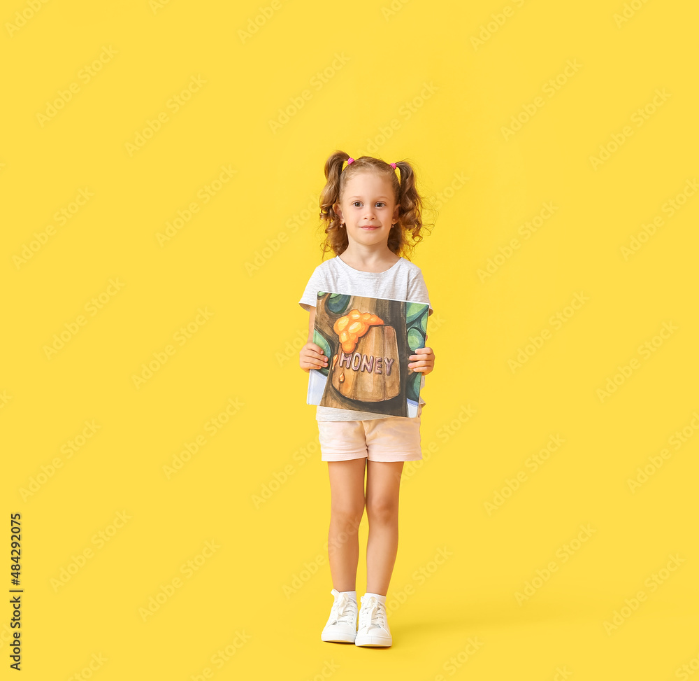 Adorable little girl with book on yellow background Adorable little girl with book on yellow background