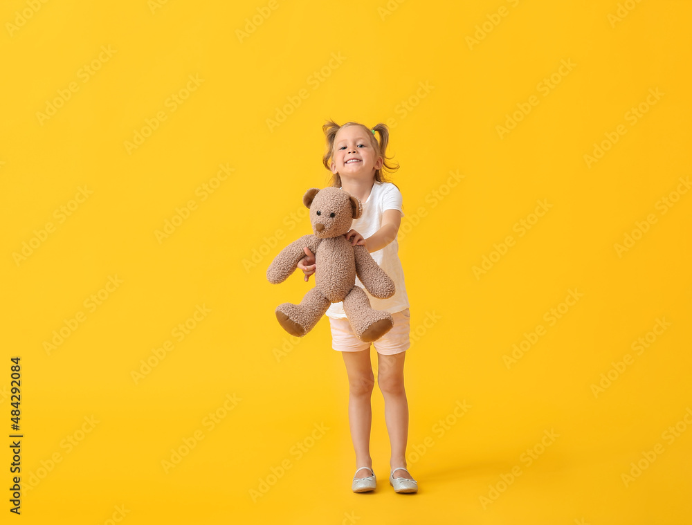Adorable little girl with teddy bear on yellow background Adorable little girl with teddy bear on yellow background