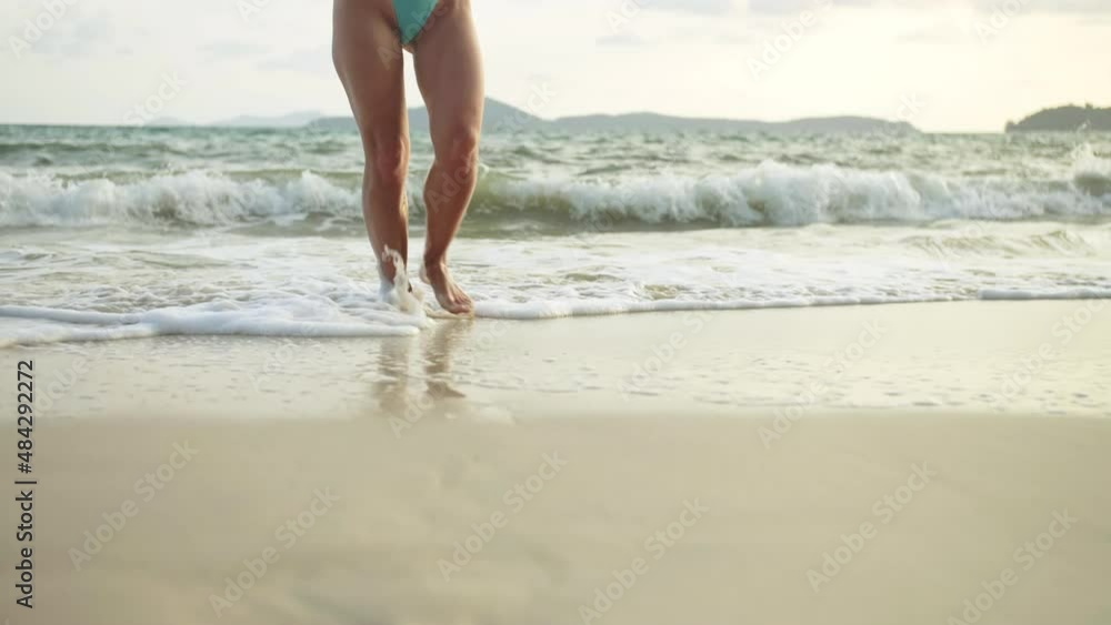 The woman feet relaxed are lying on the sandy beach and washed by the water and foam of the ocean The woman feet relaxed are lying on the sandy beach and washed by the water and foam of the ocean