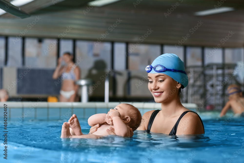 Female coach teaching little baby how to swim in pool