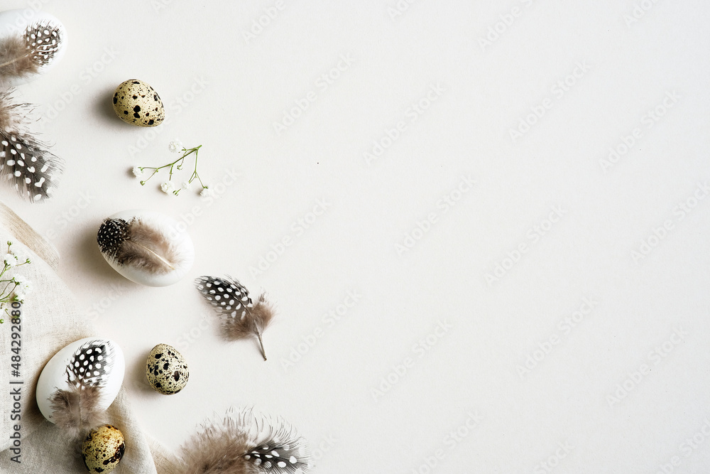 Obraz premium Elegant Easter flatlay composition. Stylish Easter eggs decorated feathers with gypsophila flowers on white table. Flat lay, top view, copy space.
