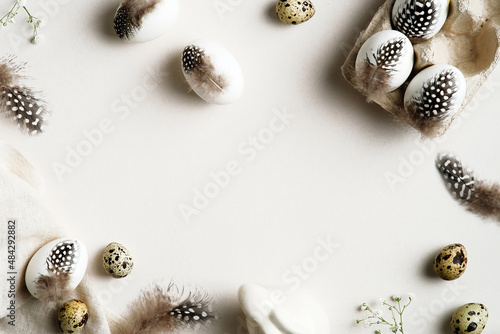 Minimal style Easter eggs decorated feathers, bunny rabbit, gypsophila leaves on white table. Happy Easter greeting card template. © photoguns