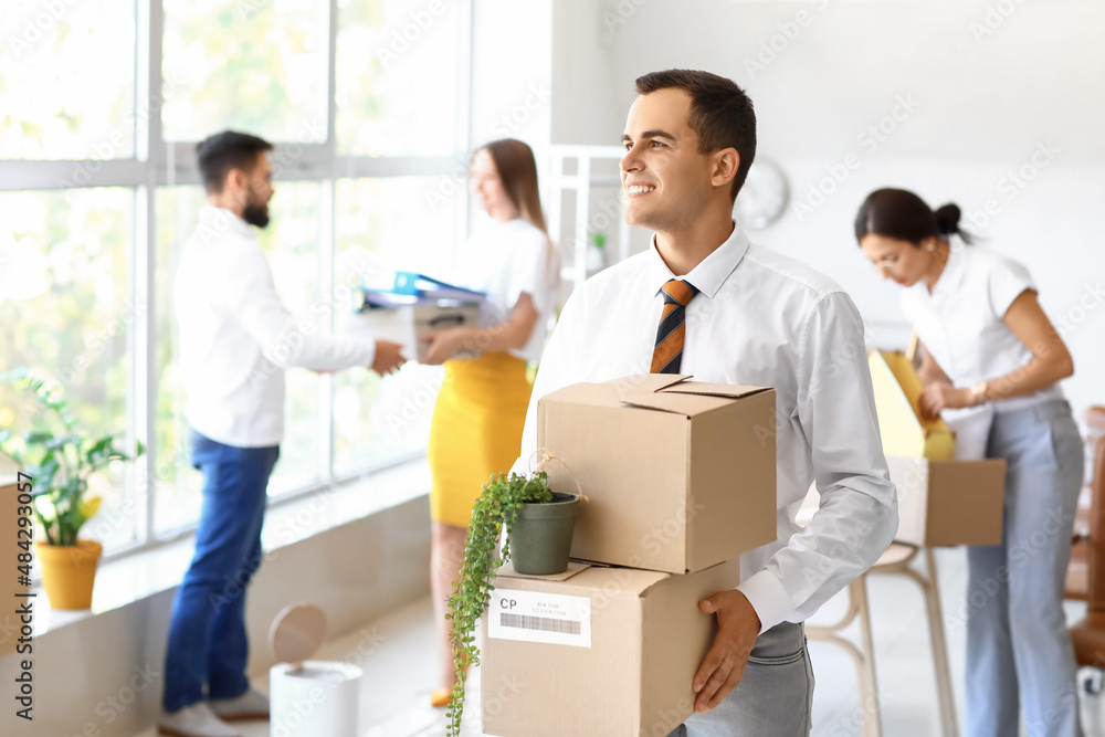 Young man holding boxes with things in office on moving day Young man holding boxes with things in office on moving day