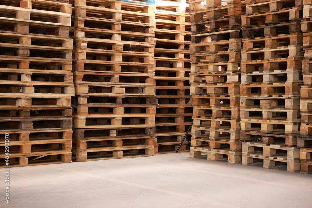 Many empty wooden pallets stacked in warehouse