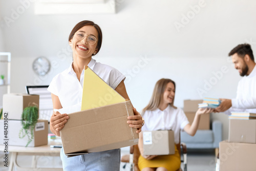 Beautiful woman holding box with things in office on moving day