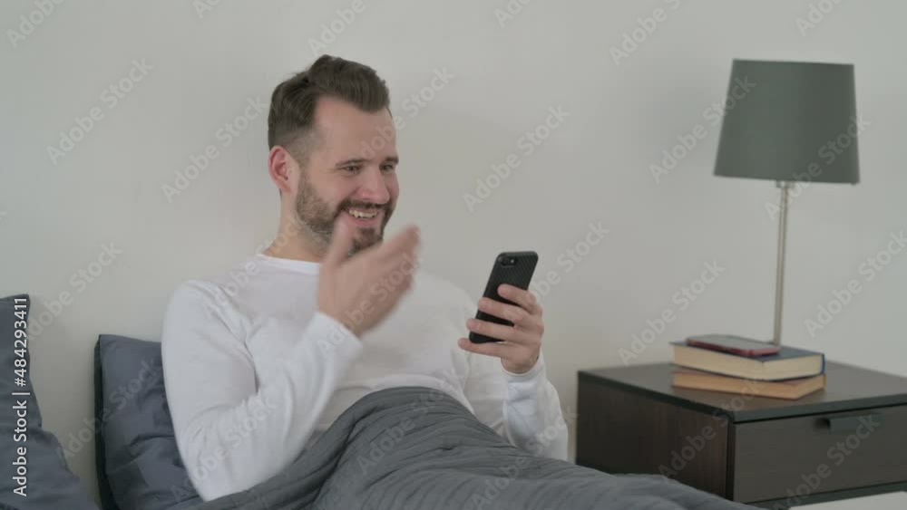 Man Celebrating Success on Smartphone in Bed Man Celebrating Success on Smartphone in Bed