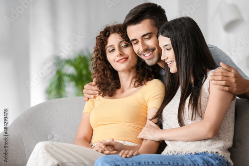 Man with two beautiful women at home. Polyamory concept photo