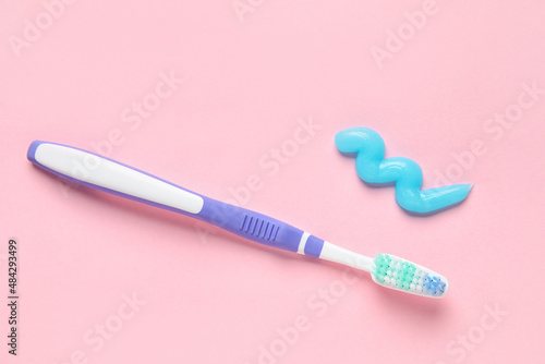Sample of toothpaste and brush on pink background