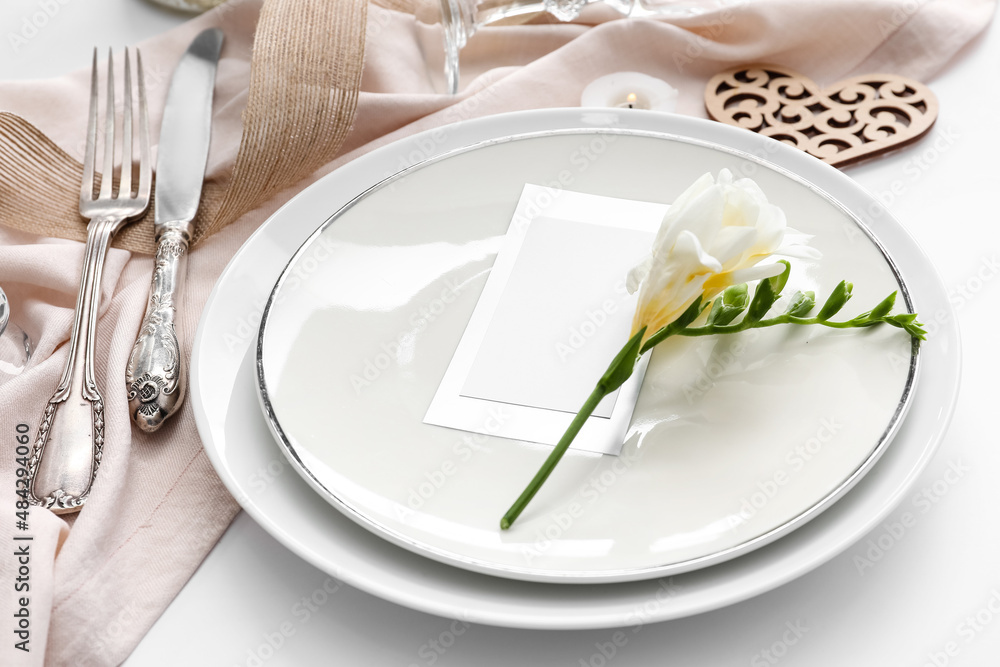 Beautiful table setting for wedding, flowers and blank card on light background Beautiful table setting for wedding, flowers and blank card on light background
